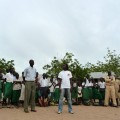 Ikal Angelei and the headteacher Mr Keem address the students, as Mr Kenyaman, the scoutmaster and a champion for tree-planting looks on.