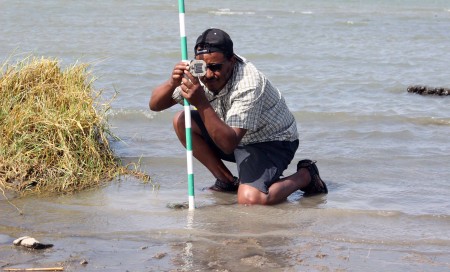 Tadele levels the jacobstaff with a brunton compass. This will provide one accurate data point to measure changes in elevation going from the shore into the water.
