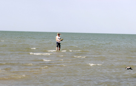 Milena wades out into the water to collect elevation data.